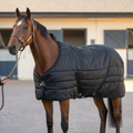 Virolla Stable Rug Standard 100g Black - bay thoroughbred in premium quilted black stable rug, three-quarter front hero with handler engaged in stable yard